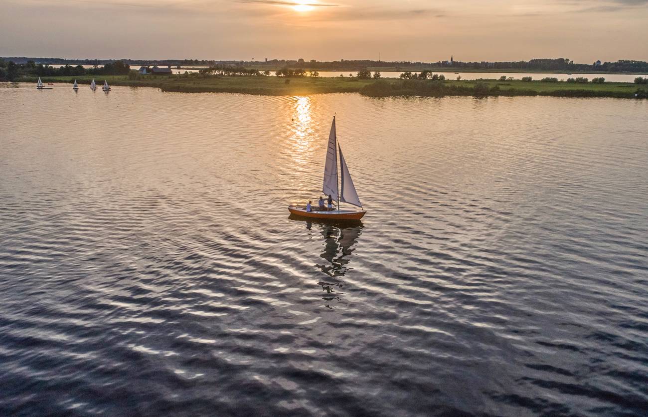 Zeilboot op het water bij zonsondergang vanuit de lucht
